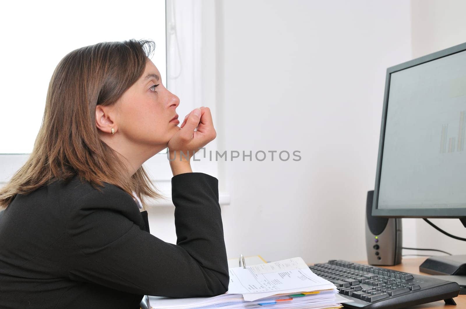 Tired and bored young business woman in depression sitting at computer on workplace