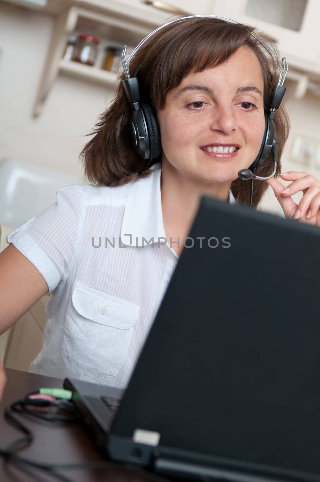 Young business person with headache working at home and calling (headset on head)