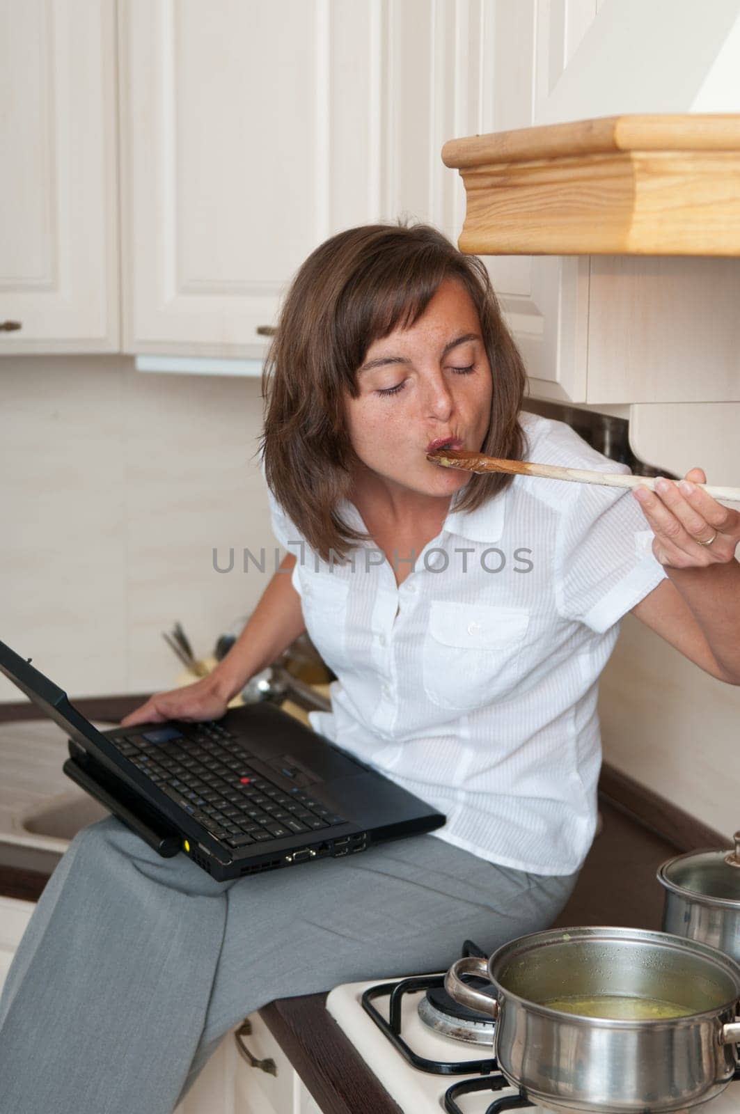 Multitasking woman - cooking meal and working