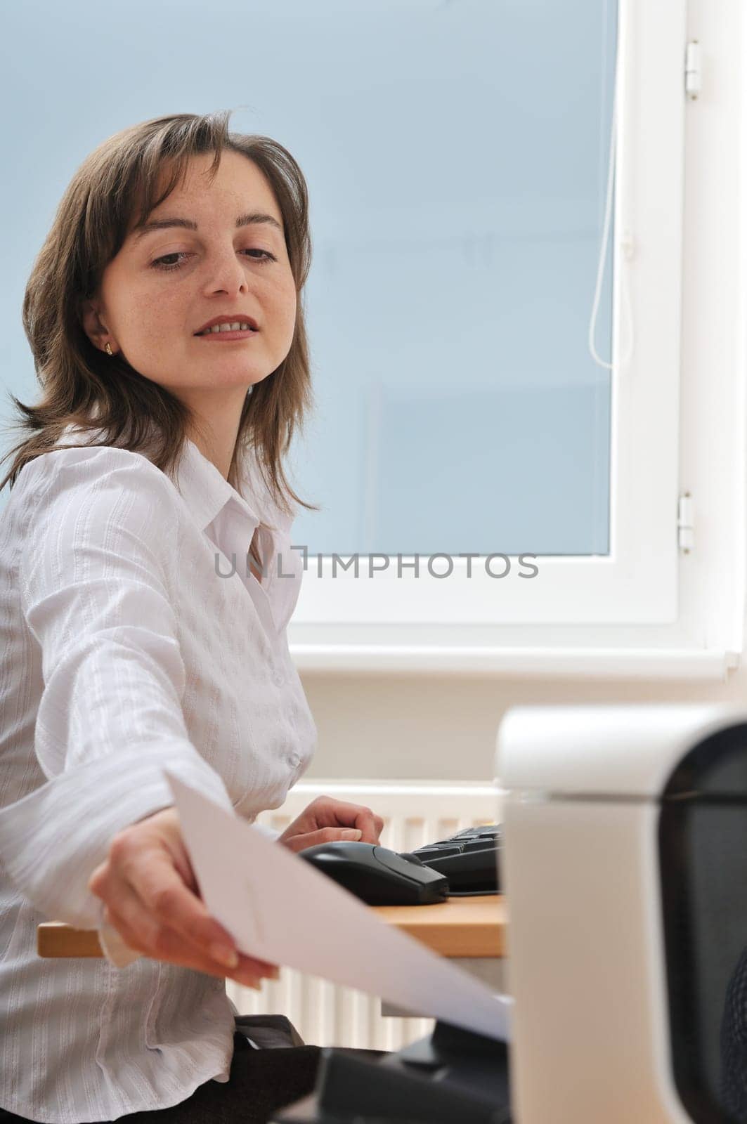 Business person reaching hand and taking paper from printer on workplace - detail