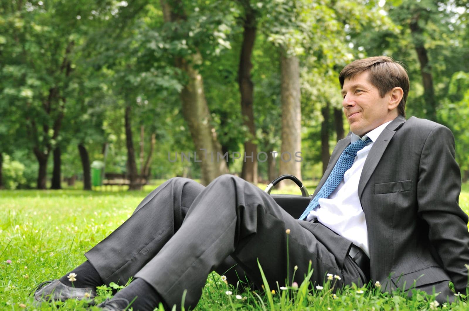 Senior people series - mature business man siting on grass and relaxing in nature