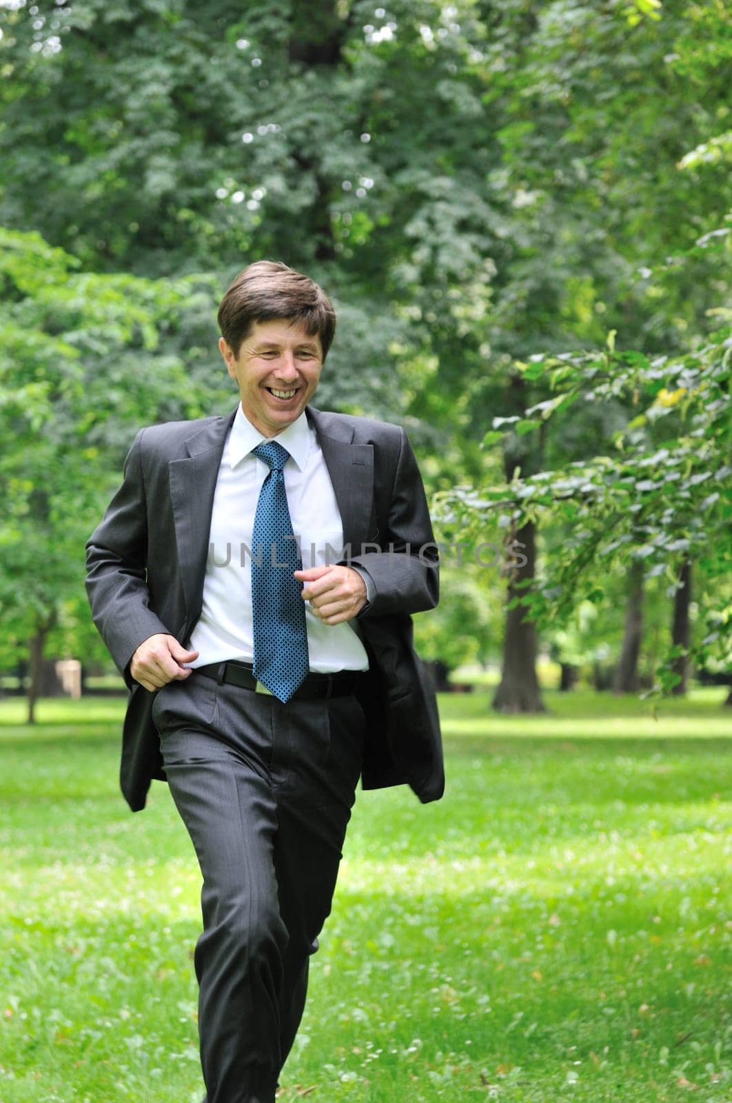 Escape from civilization - smiling senior business man running in park