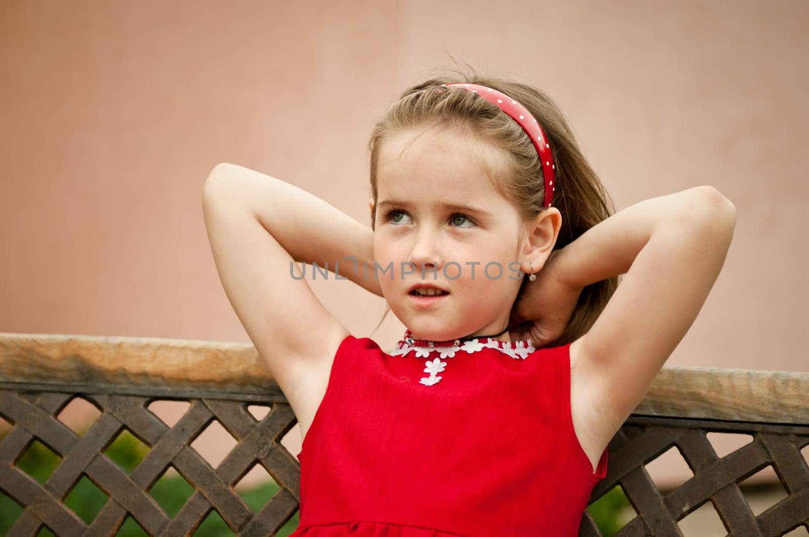 Portrait of small girl putting necklace on neck looking away