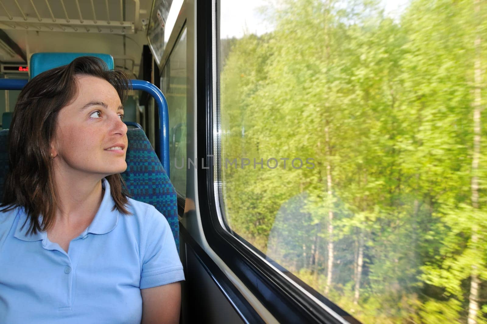 Young woman passanger sitting inside train and looking trough window