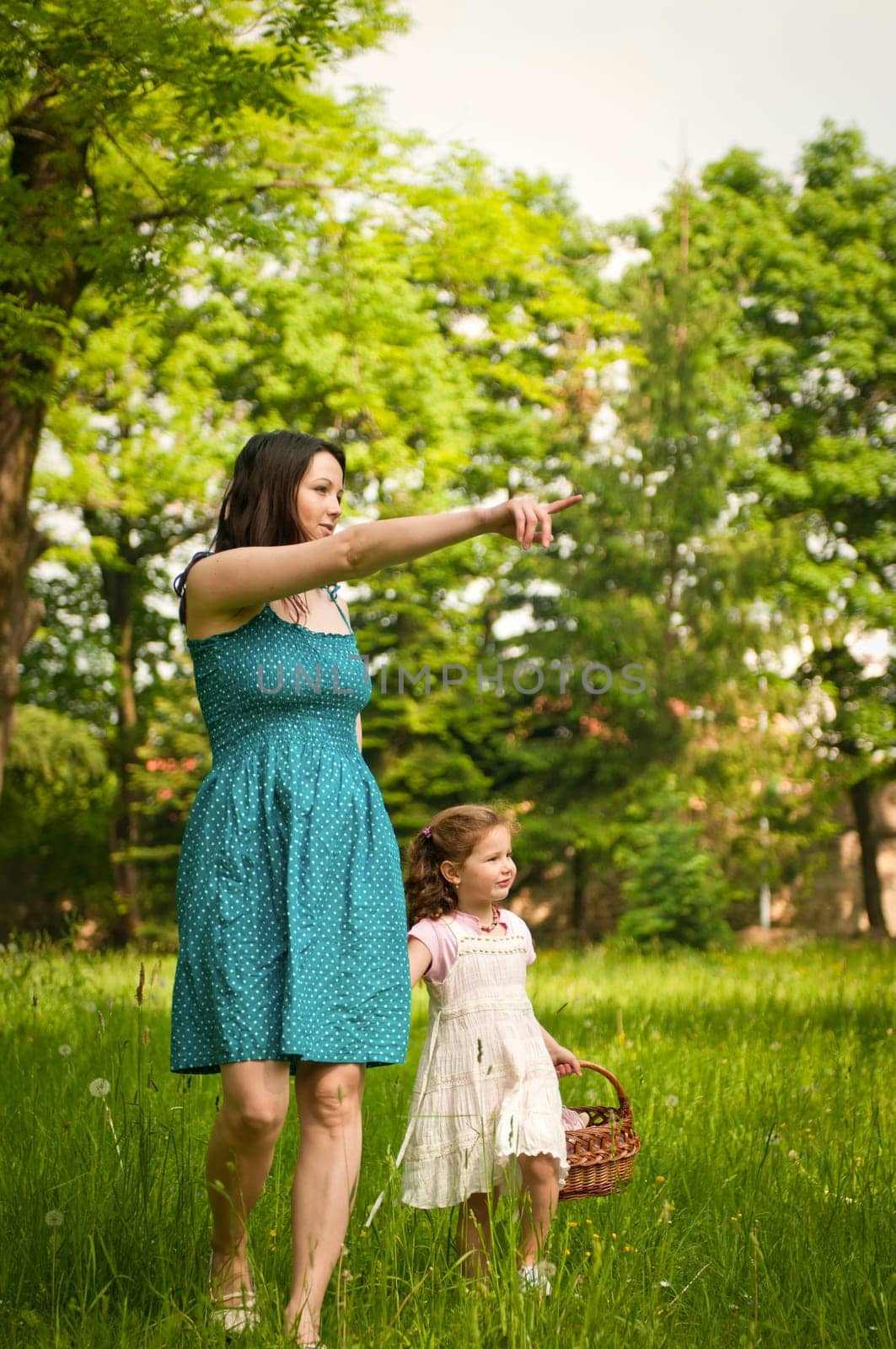 Mother shows with finger to her cute little daughter something interesting in distance