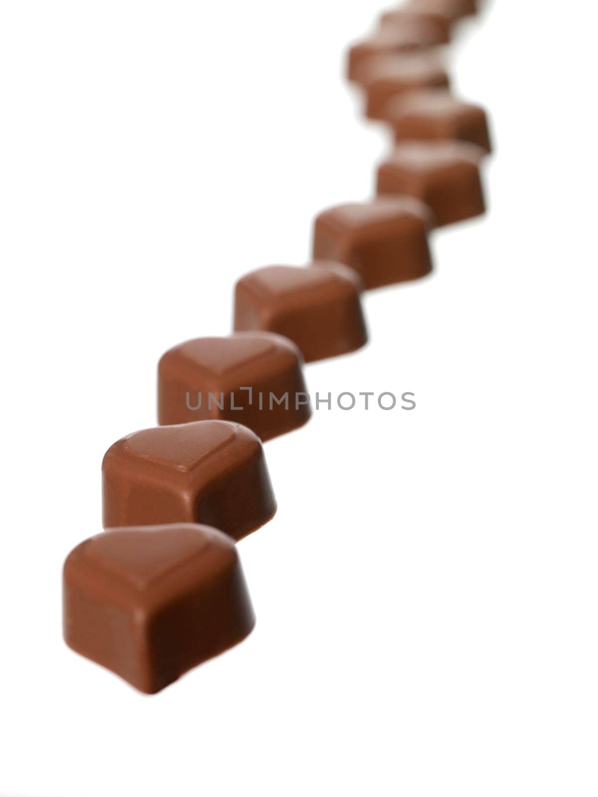 Heart shaped chocolate in a row on white background