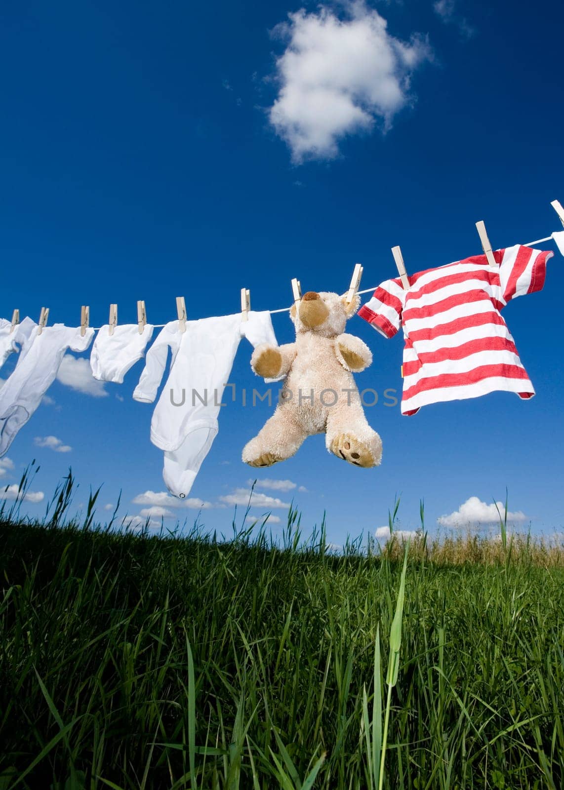 Baby Clothing and a teddybear on a clothesline towards blue sky
