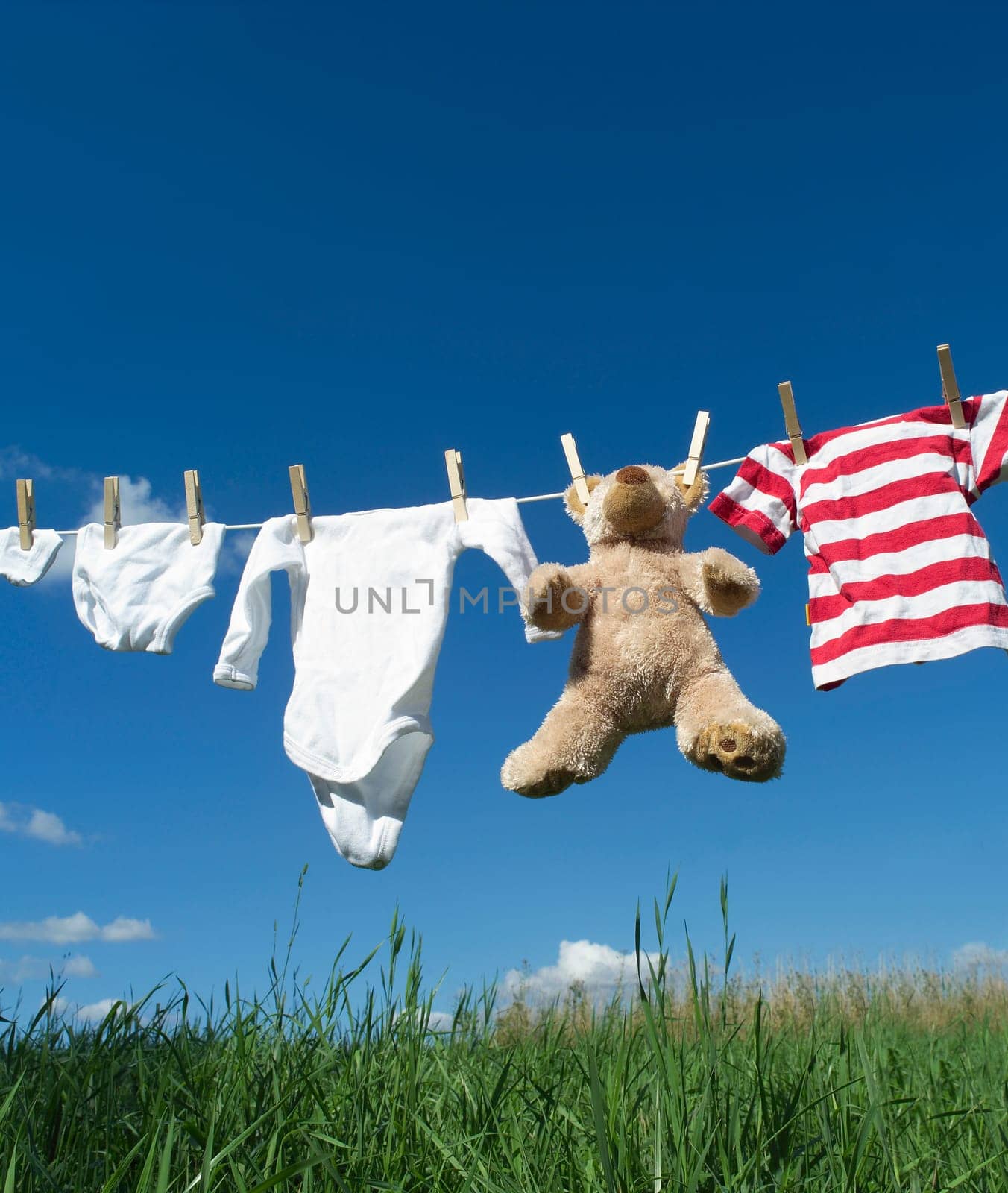 Baby Clothing and a teddybear on a clothesline towards blue sky