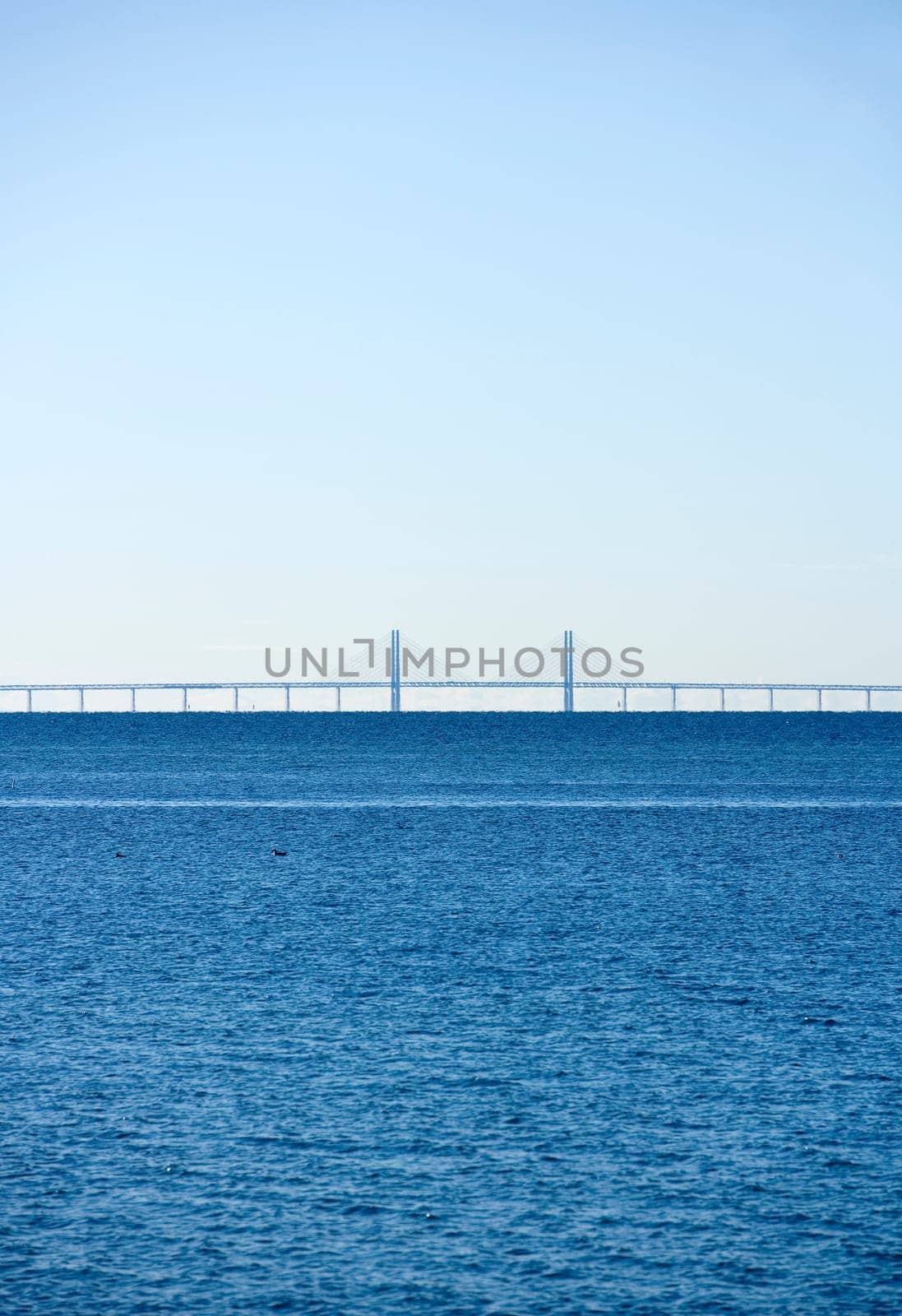 Horizon over Water on a sunny day with a bridge in the background