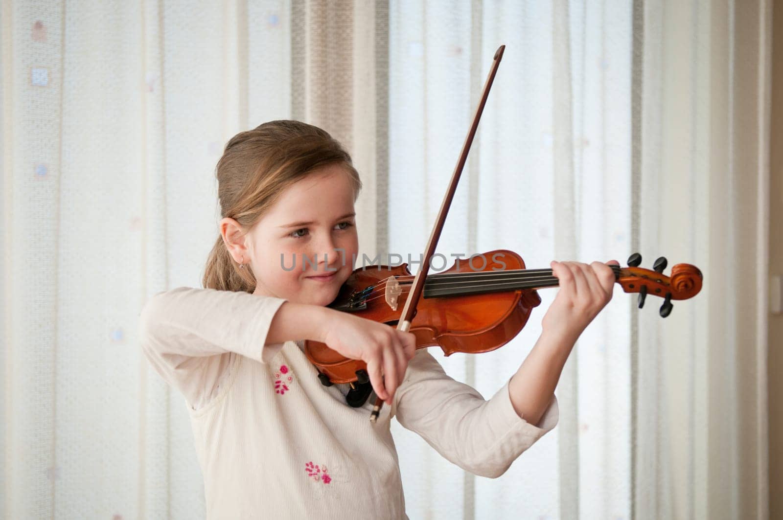 Cute child (little girl) playing violin and exercising at home