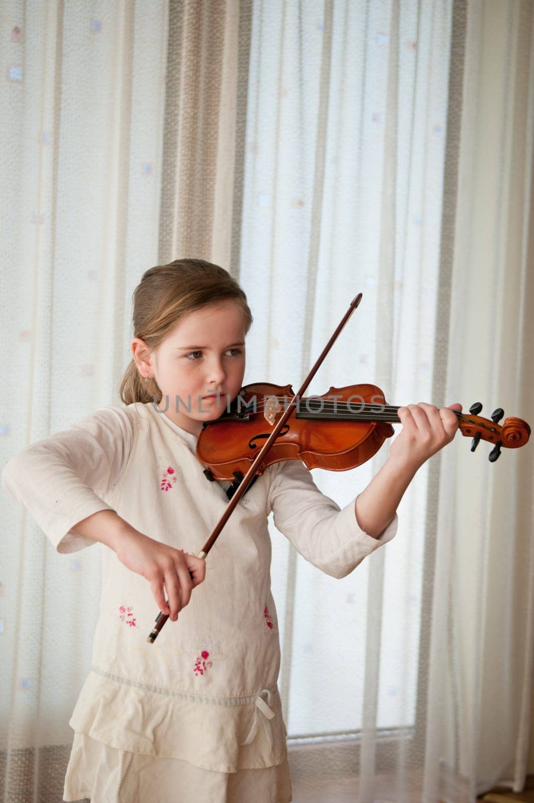 Cute child (little girl) playing violin and exercising at home