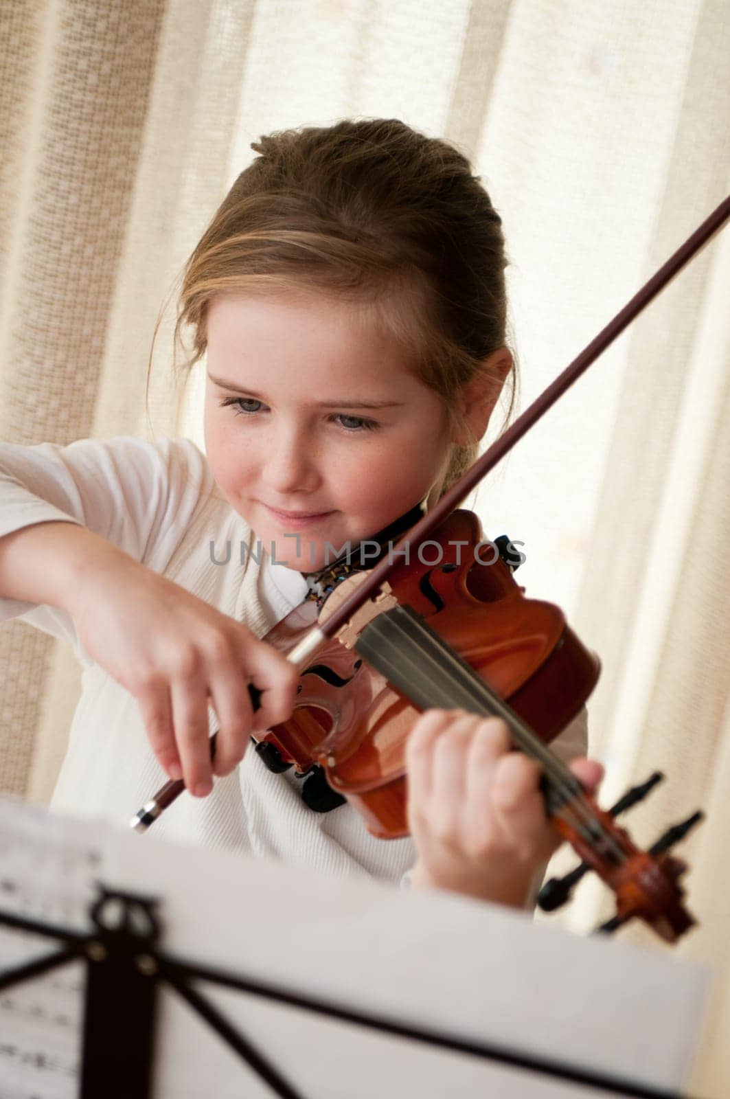 Cute child (little girl) playing violin and exercising at home