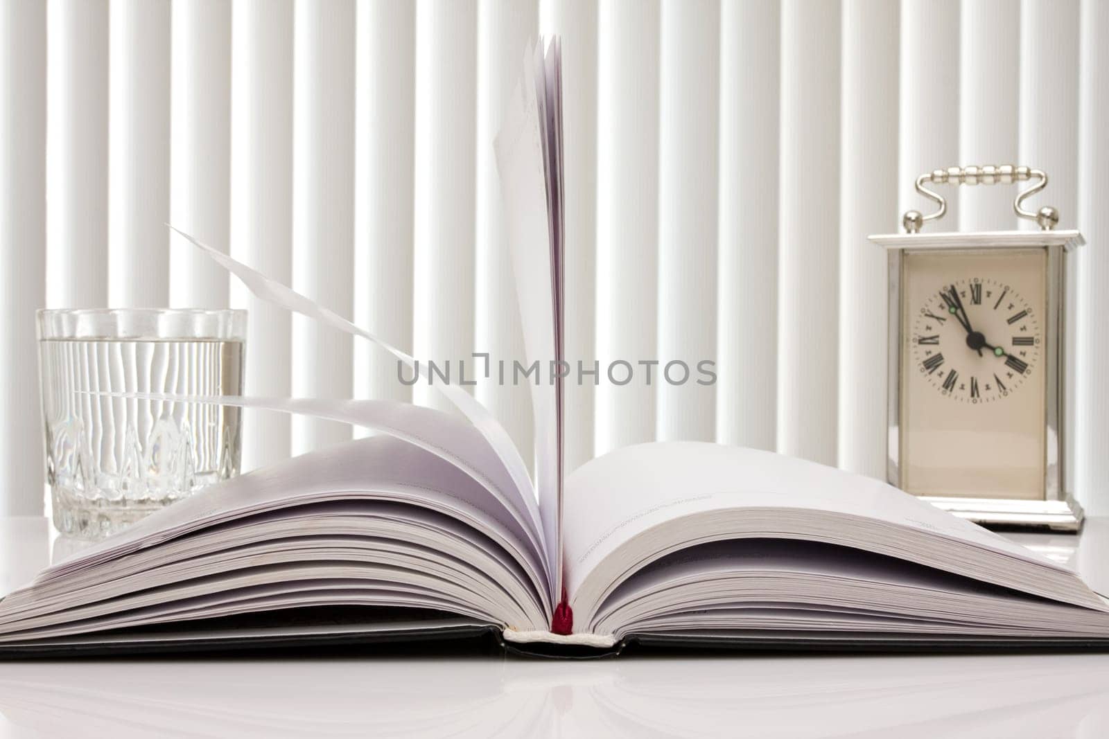 time for reading. book,clock and glass of water.