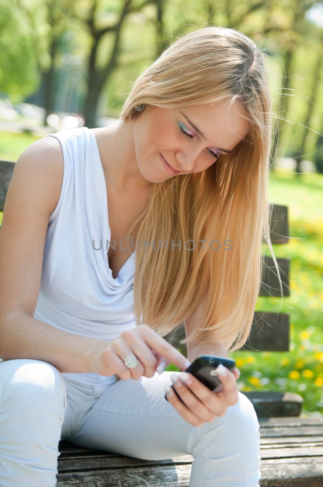 Happy teen person working with touchscreen smartphone sitting outdoors on bench