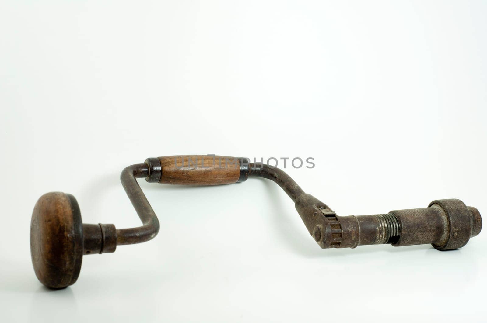 antique hand drill with wooden handles and crank on white background