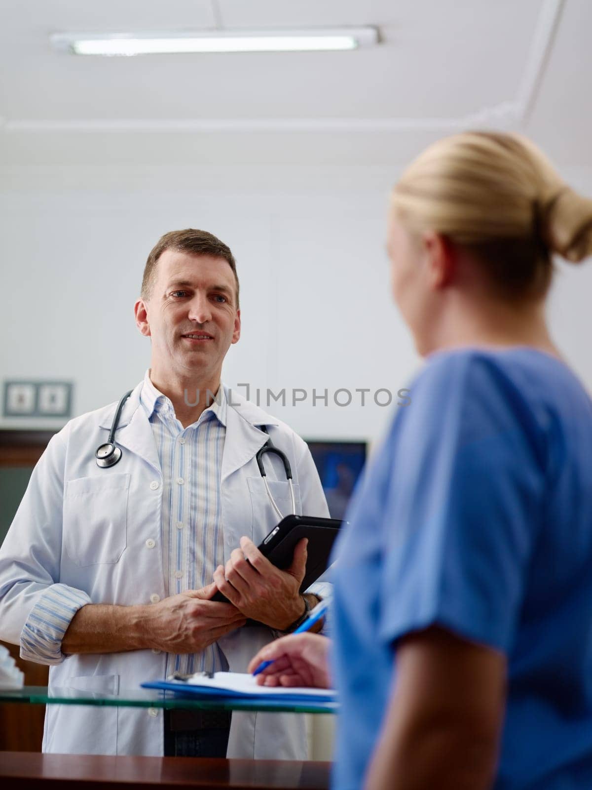 Doctor talking to young woman at work as nurse in medical clinic and taking medical file.