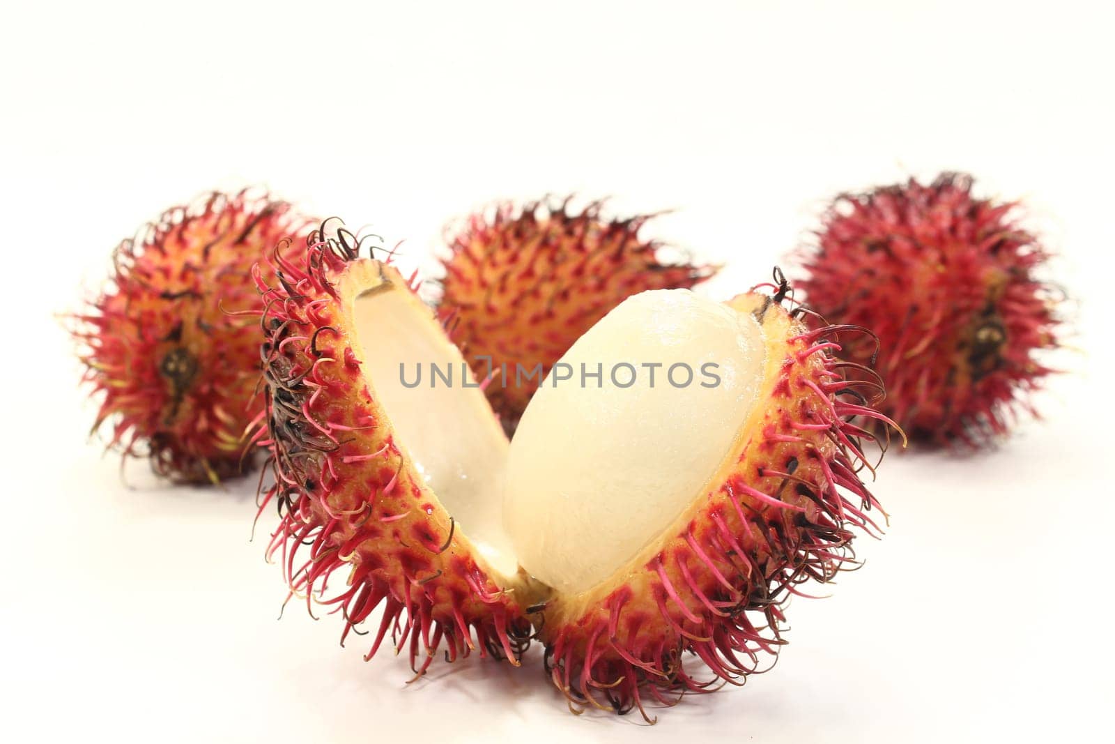 four rambutan fruits against white background