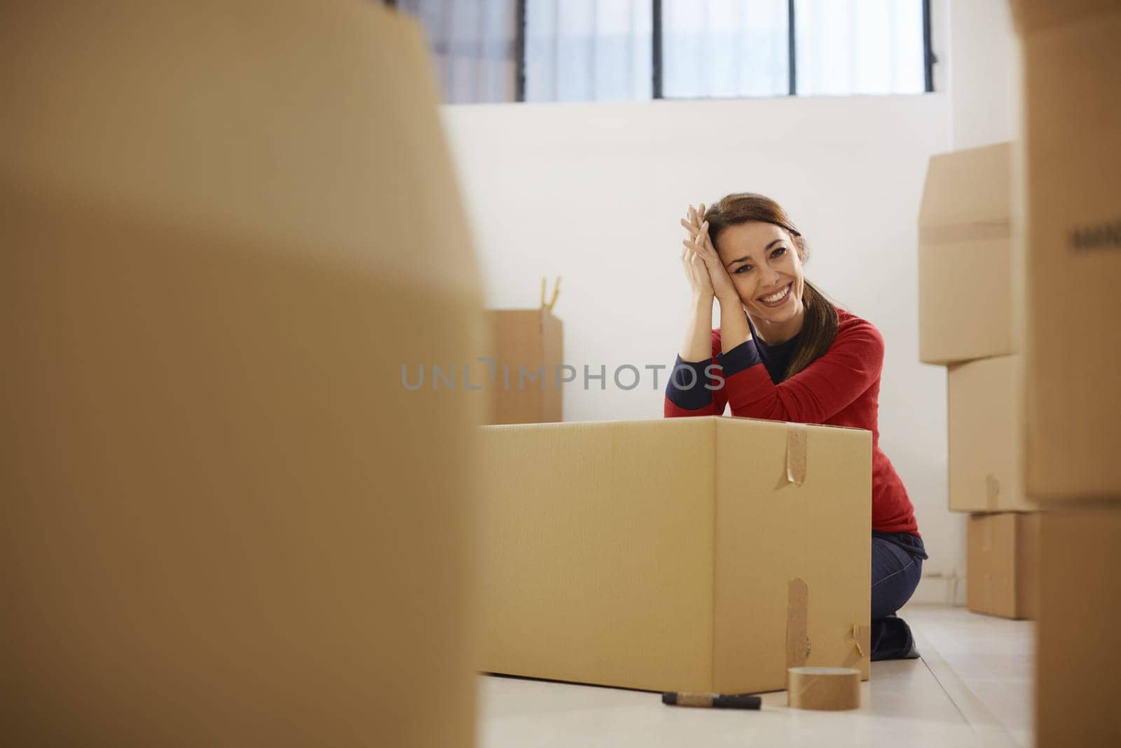 Portrait of mid adult happy woman moving with boxes at new apartment and looking at camera. Copy space