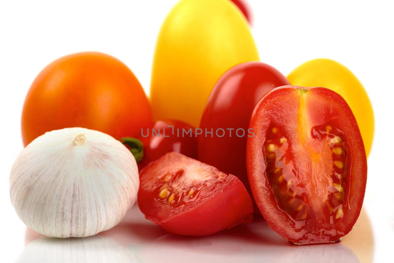 Various organic tomatoes with garlic onion on white background