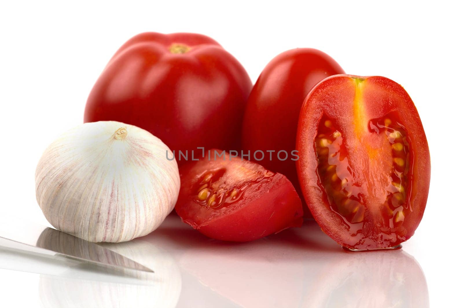 Fresh tomatoes with knife and garlic onion against white background