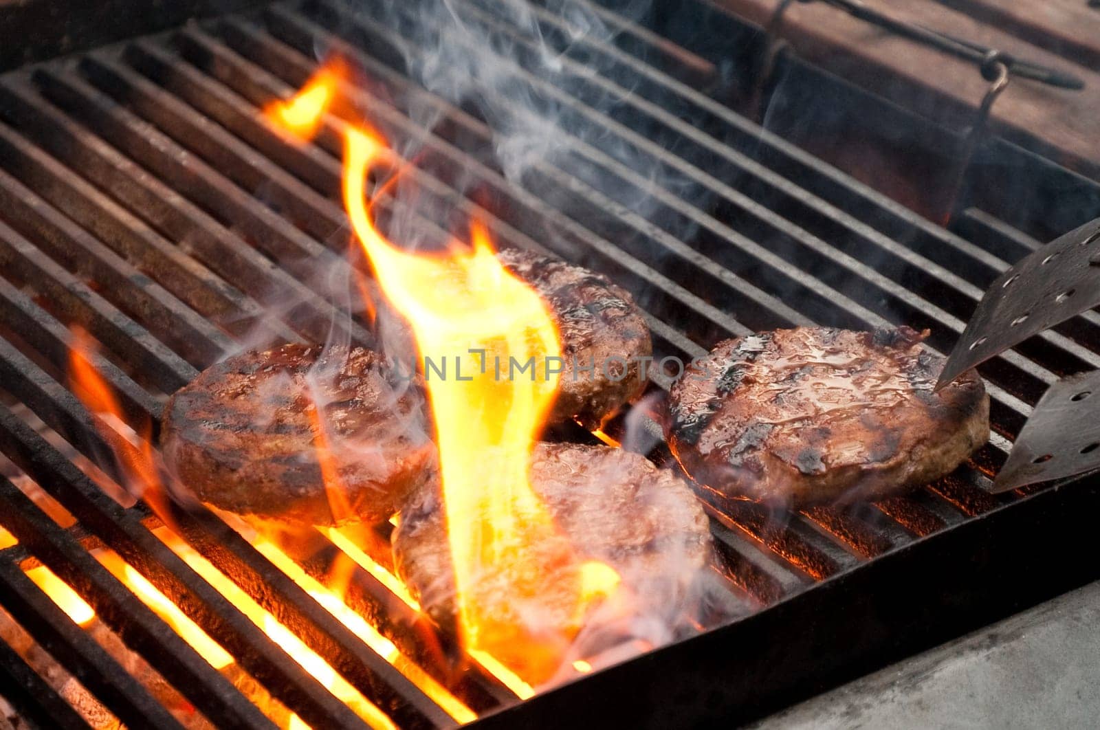 tasty burgers being cooked on a flaming barbecue
