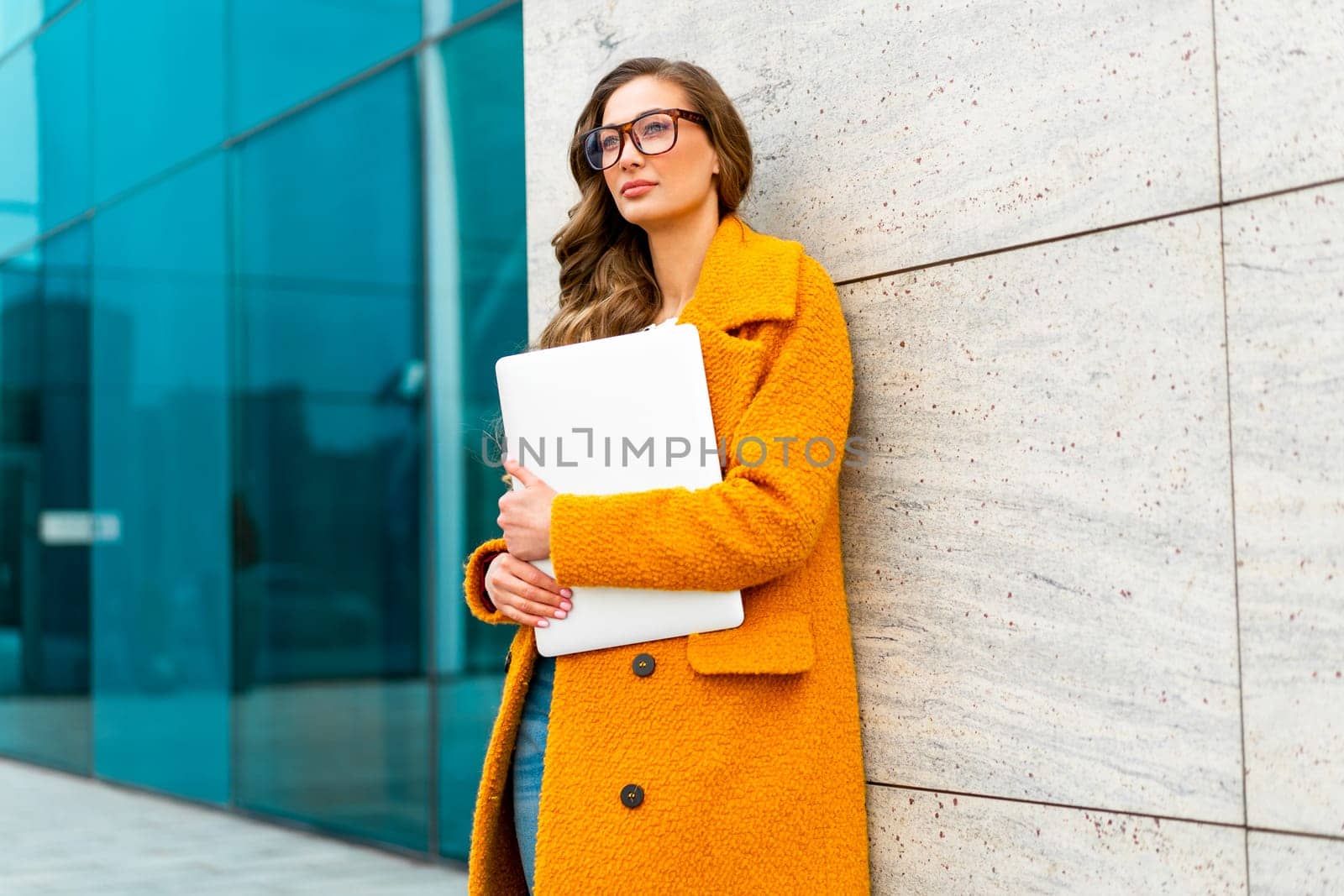 Businesswoman wear eyeglasses with laptop dressed yellow coat standing outdoors