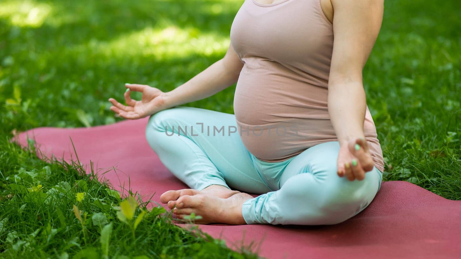 Prenatal yoga. Caucasian pregnant woman doing butterfly pose in the park