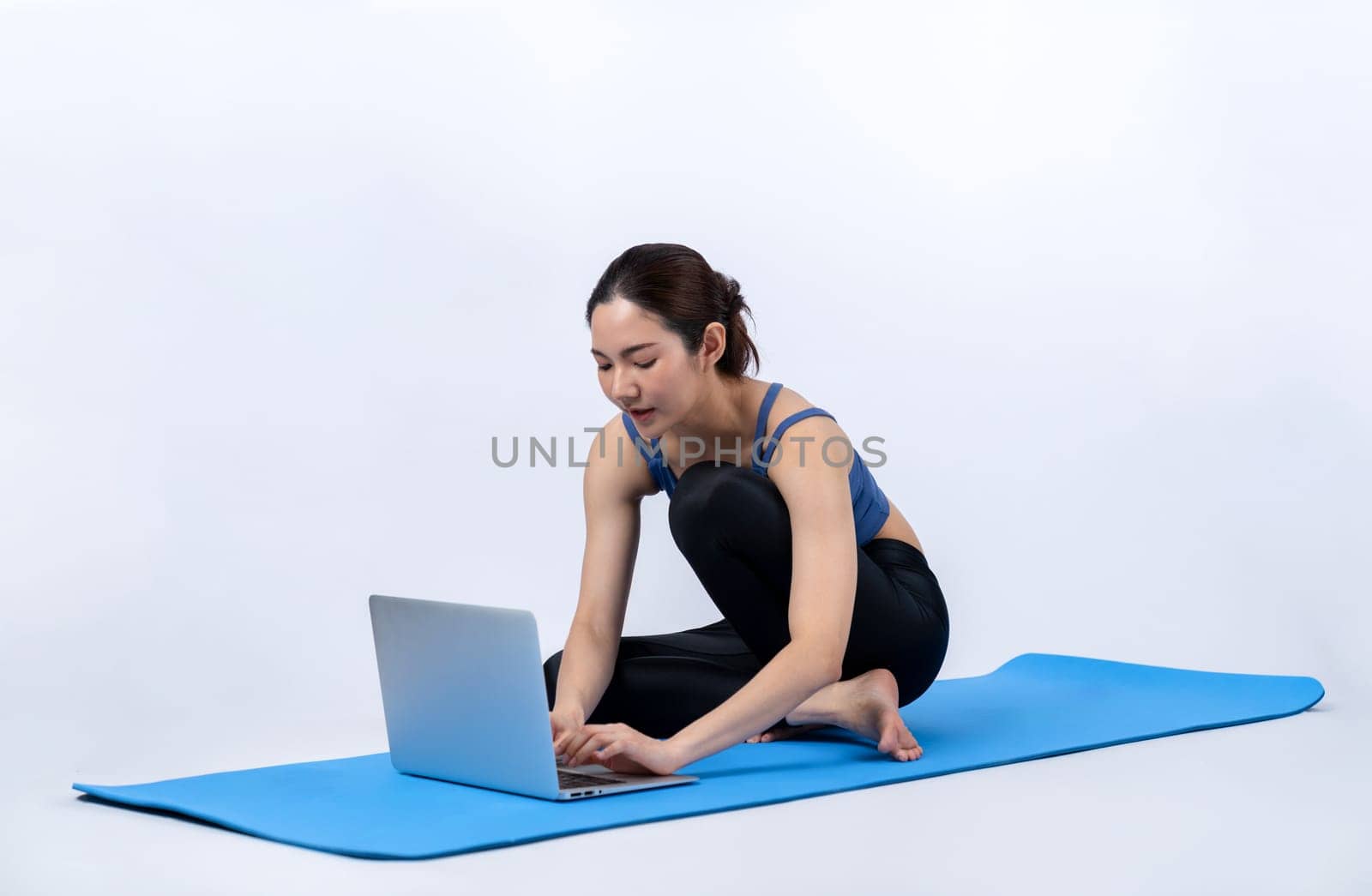 Young asian woman in sportswear stretching before fitness exercise following instruction from online video. Body workout with healthy athletic woman warming up on isolated background. Vigorous