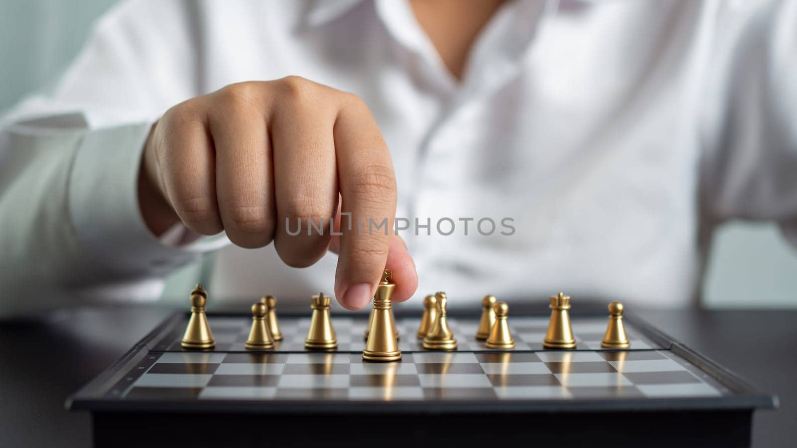 Businessman holding a king on a chess board to move forward and start the game represents Strategic planning and business planning by Unimages2527