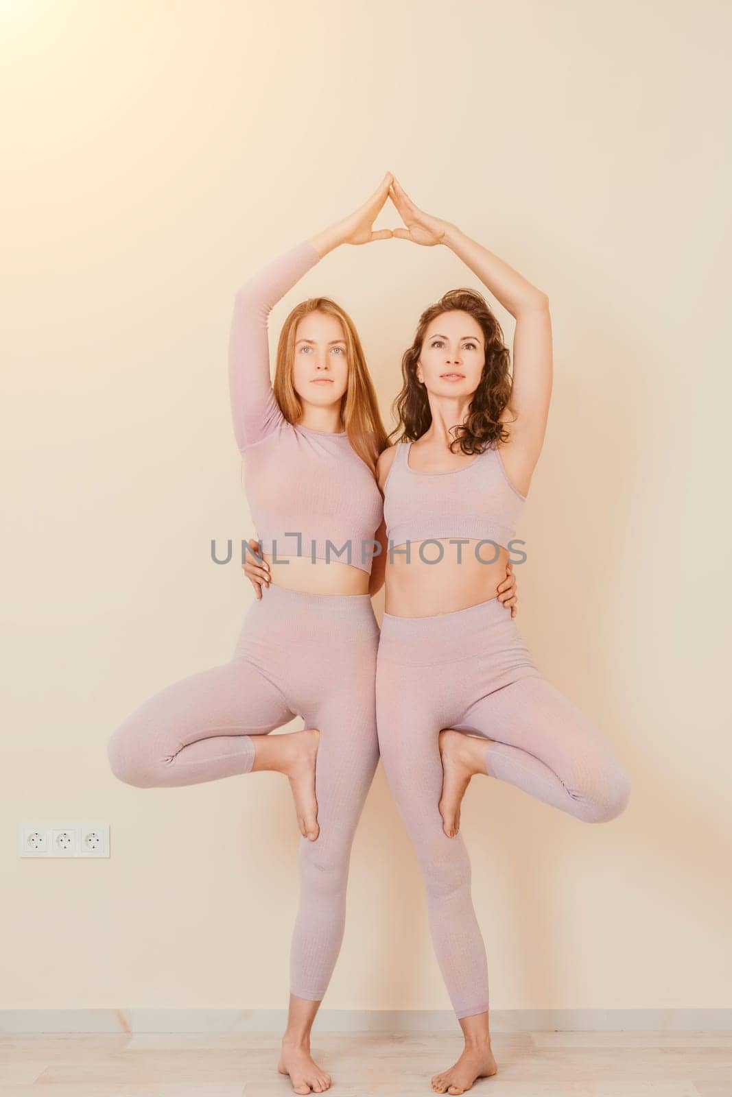 Well looking middle aged sporty woman, fitness instructor in pink sportswear doing stretching and pilates on yoga mat in the studio with mirror. Female fitness yoga. Healthy lifestyle and harmony. by panophotograph