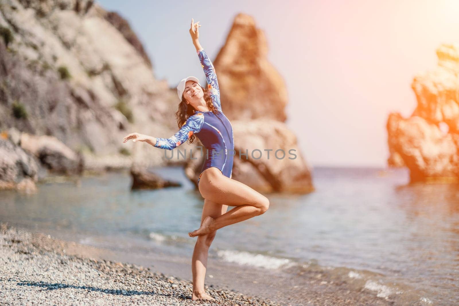 Portrait woman sea. Well looking middle aged woman with black hair, fitness instructor in blue swimwear on the rocky beach near the sea. Female fitness yoga routine concept. Healthy lifestyle. by panophotograph