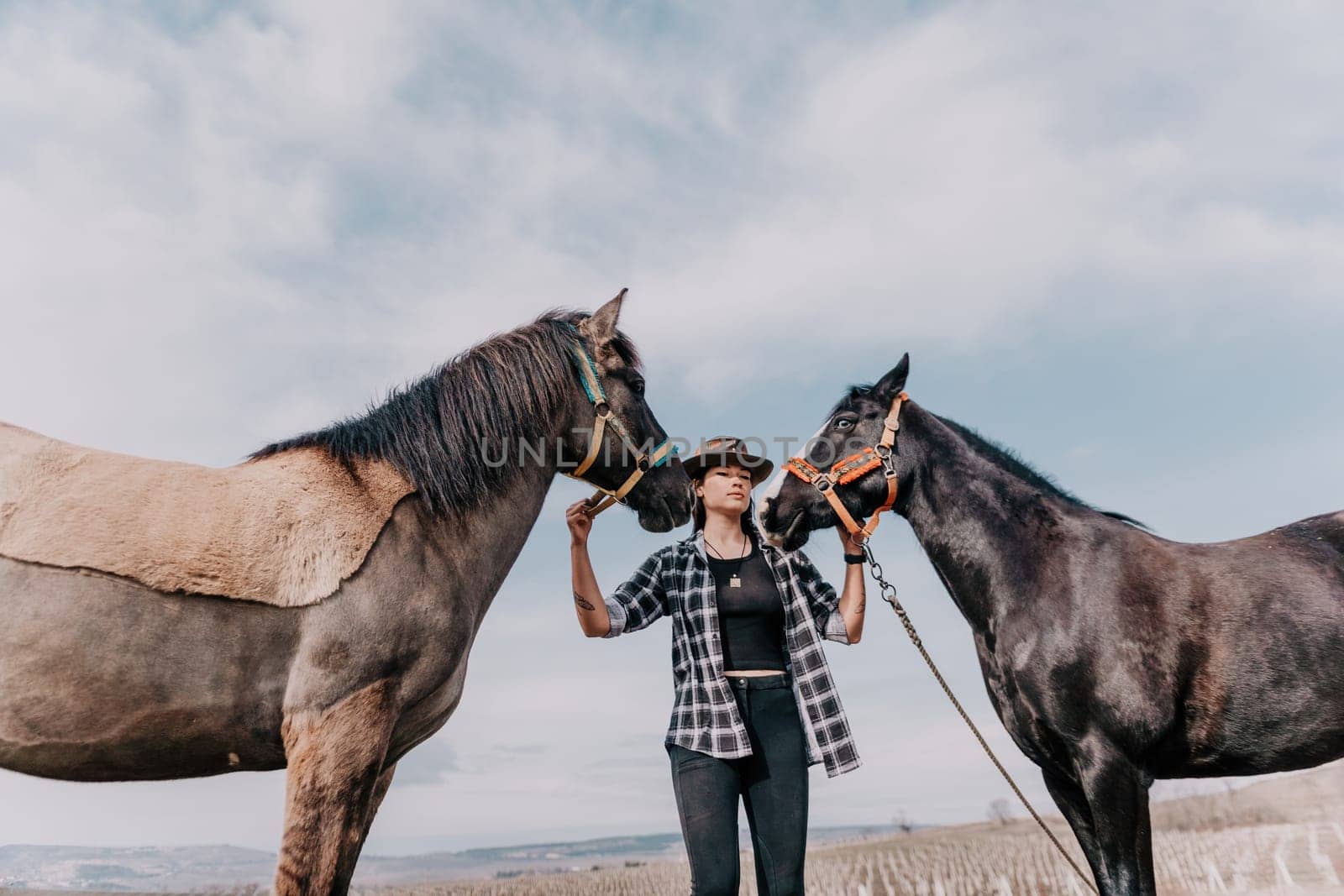 Young happy woman in hat with her horse in evening sunset light. Outdoor photography with fashion model girl. Lifestyle mood. Concept of outdoor riding, sports and recreation. by panophotograph