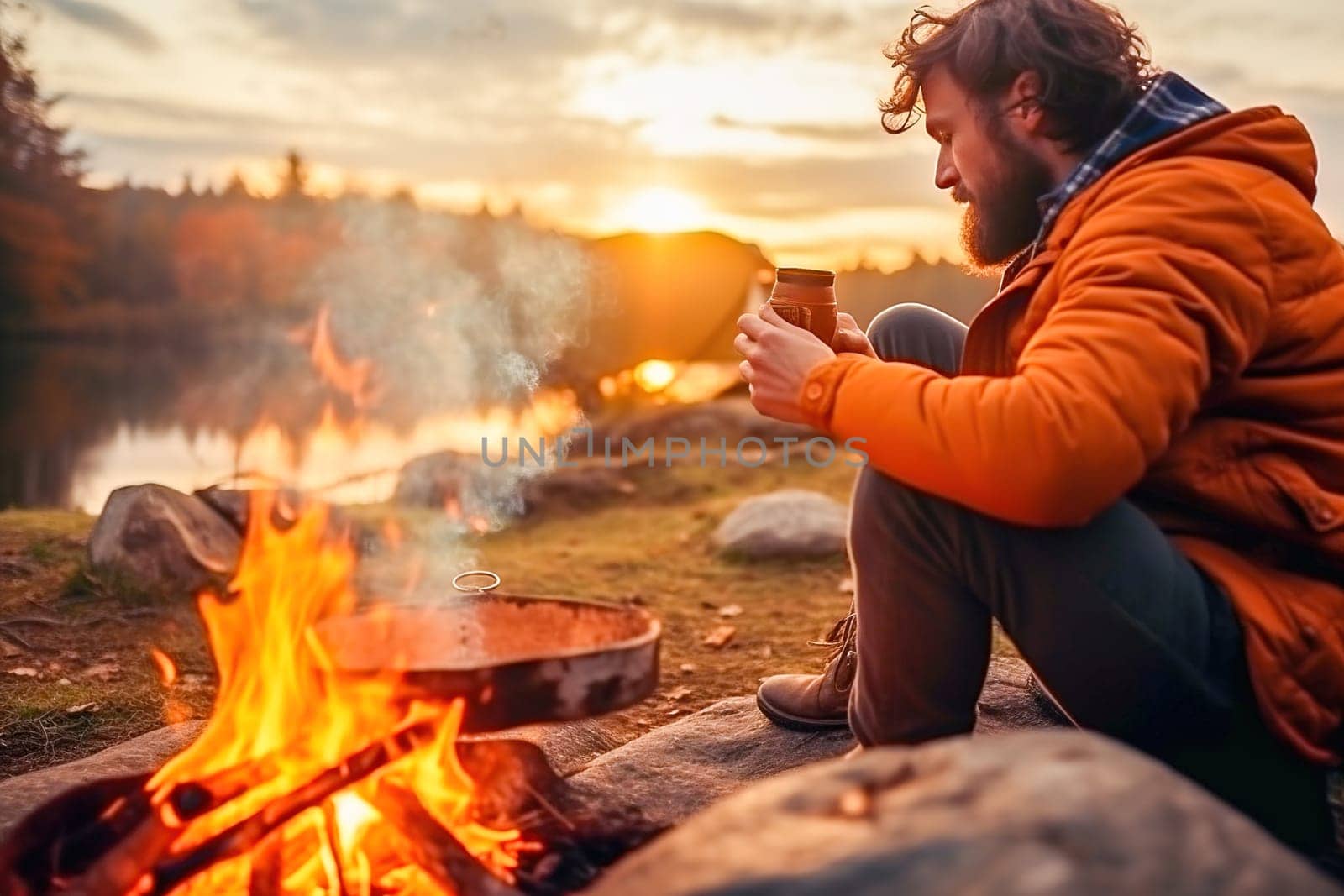 A male traveler sits by a fire in the forest. High quality photo