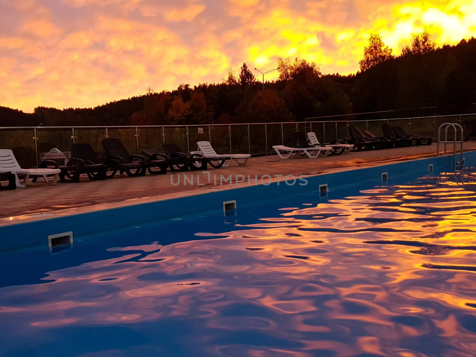 Swimming pool with sun loungers at sunset. High quality photo