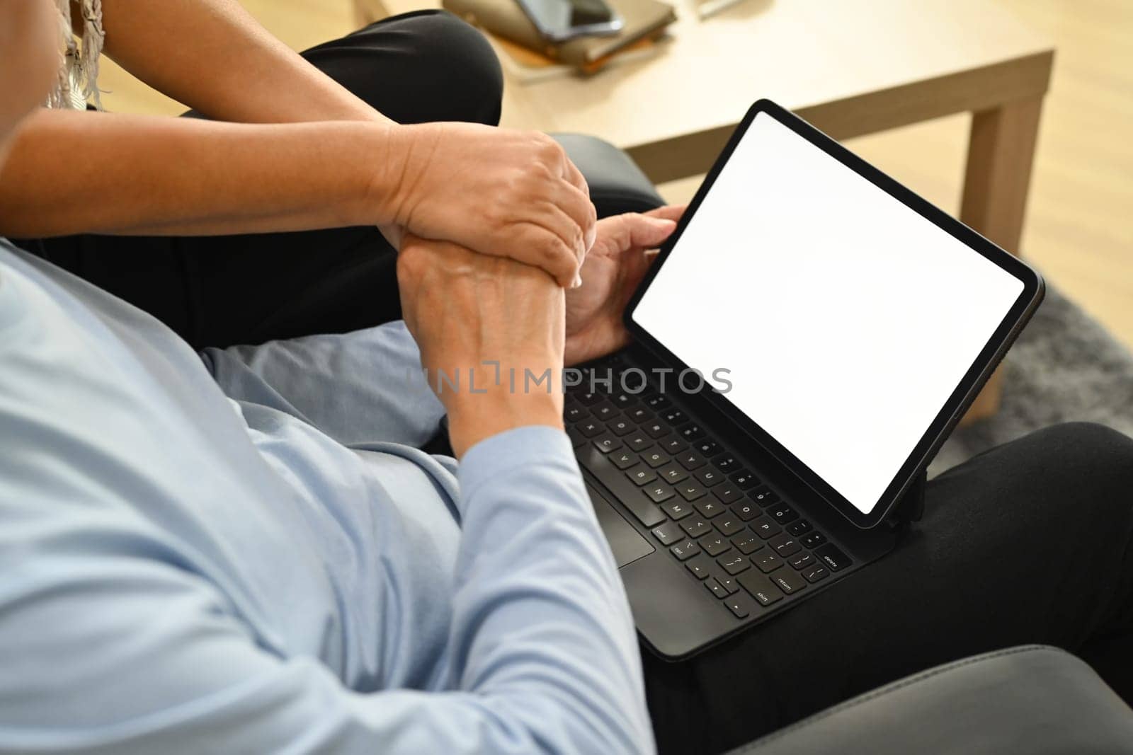 Close up view of a senior couple holding hands and watching something on digital tablet by prathanchorruangsak