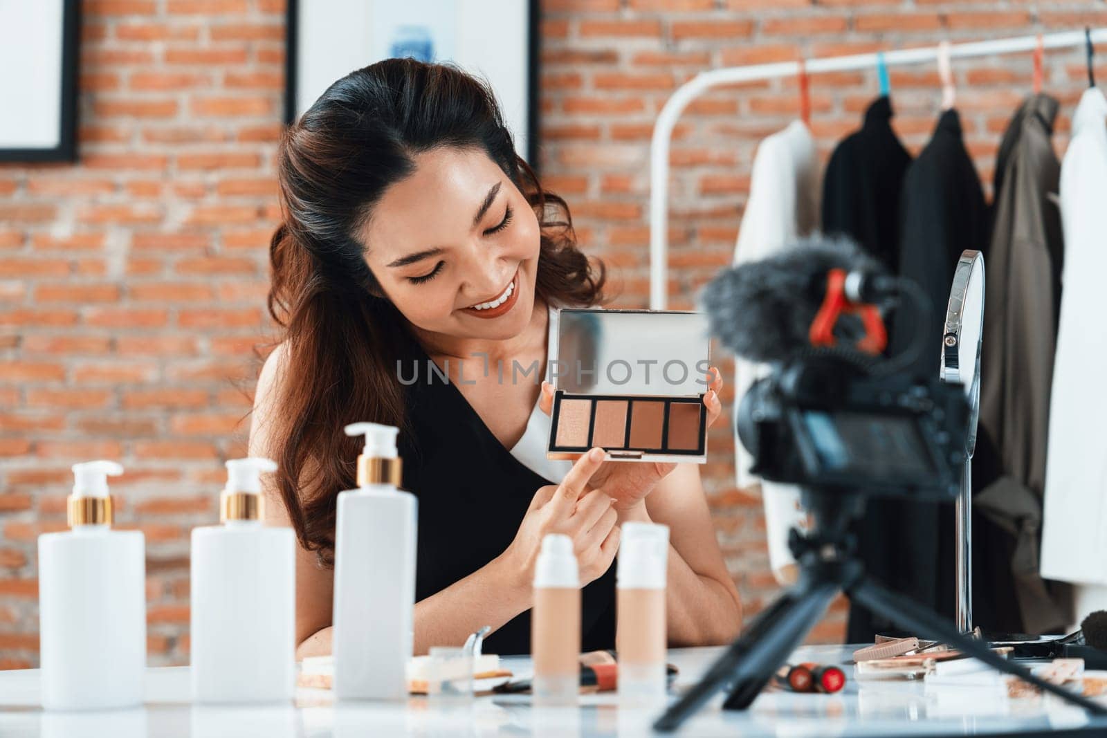 Woman influencer shoot live streaming vlog video review makeup uttermost social media or blog. Happy young girl with cosmetics studio lighting for marketing recording session broadcasting online.