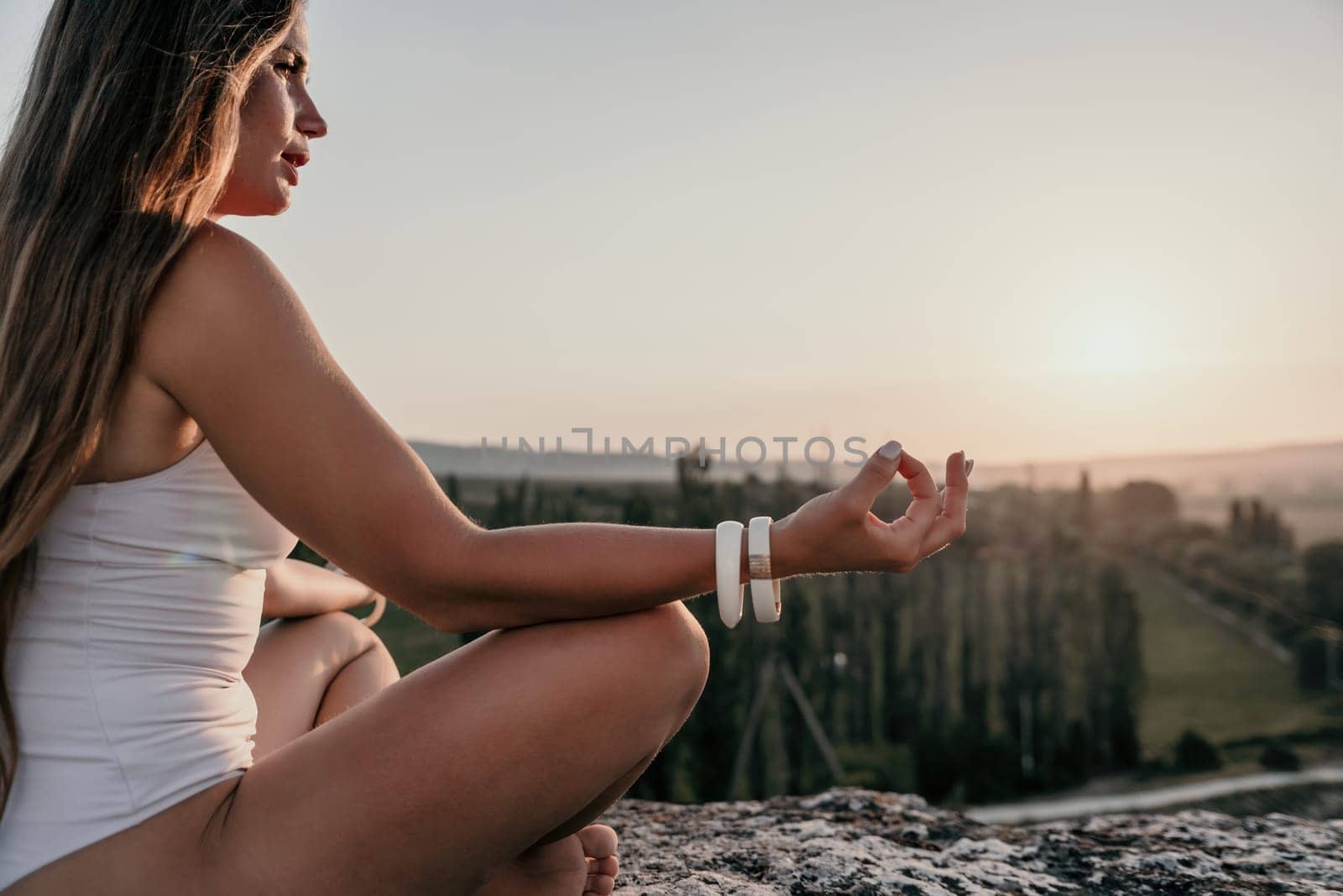 Well looking middle aged woman with long hair, fitness instructor in leggings and tops doing stretching and pilates on the rock near forest. Female fitness yoga routine concept. Healthy lifestyle by panophotograph