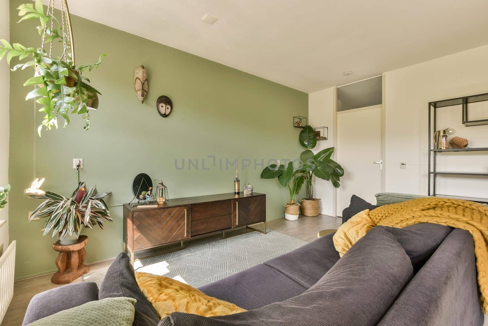 a living room with couches, plants and a tv set on the wall in the room is bright green