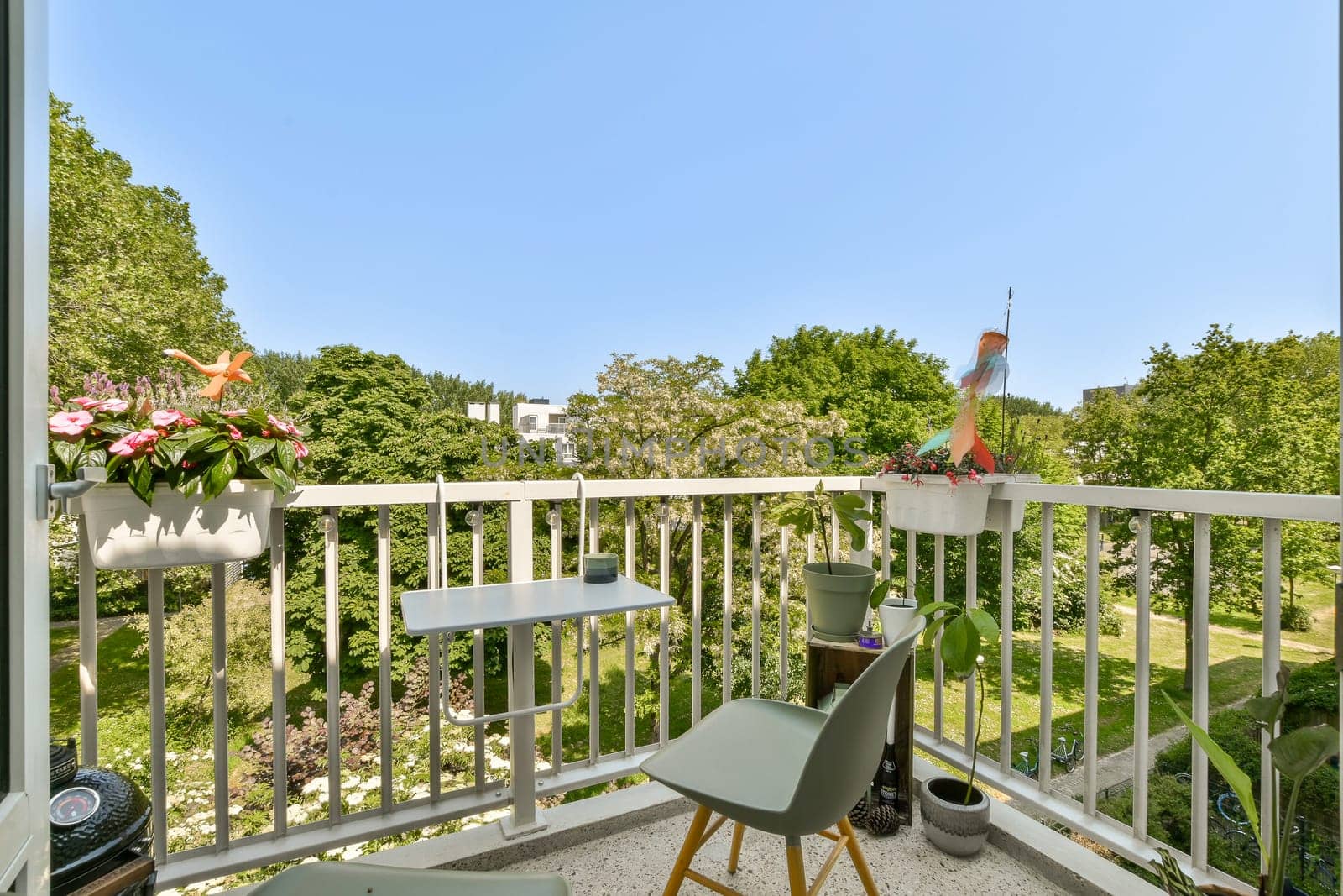 a balcony with two chairs and a table on the outside, looking out onto the trees in the back yard