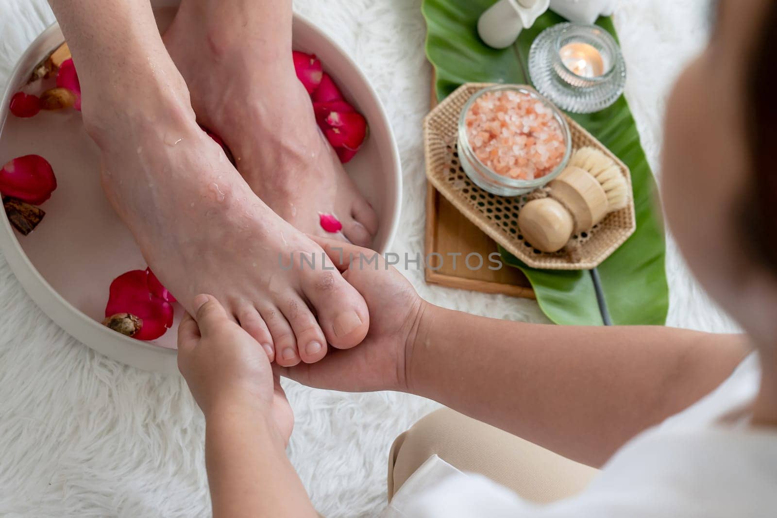 Woman indulges in blissful foot massage at luxurious spa salon while masseur give reflexology therapy in gentle day light ambiance resort or hotel foot spa. Quiescent