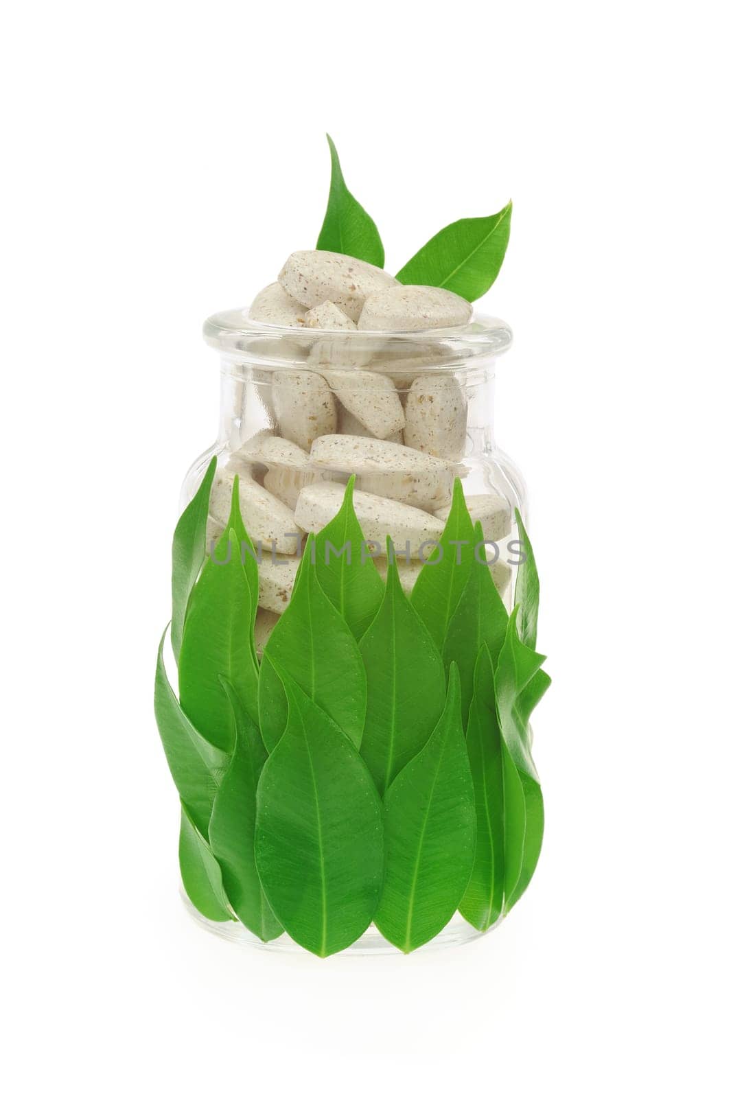 Herbal supplement pills and fresh leaves in glass - alternative medicine concept