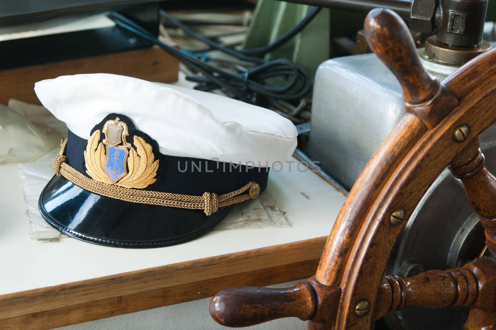 Workplace of the captain. Still-life on marine subject matter with a peak-cap and a steering wheel