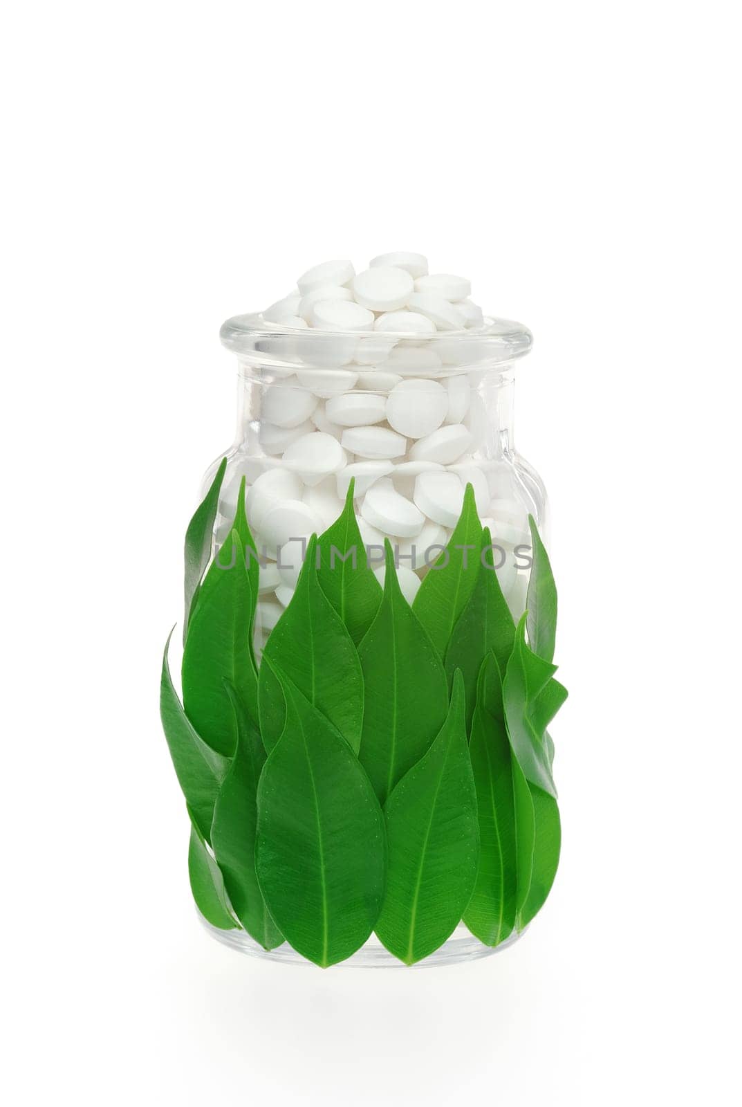 Herbal supplement pills in pill bottle with fresh leaves - alternative medicine concept