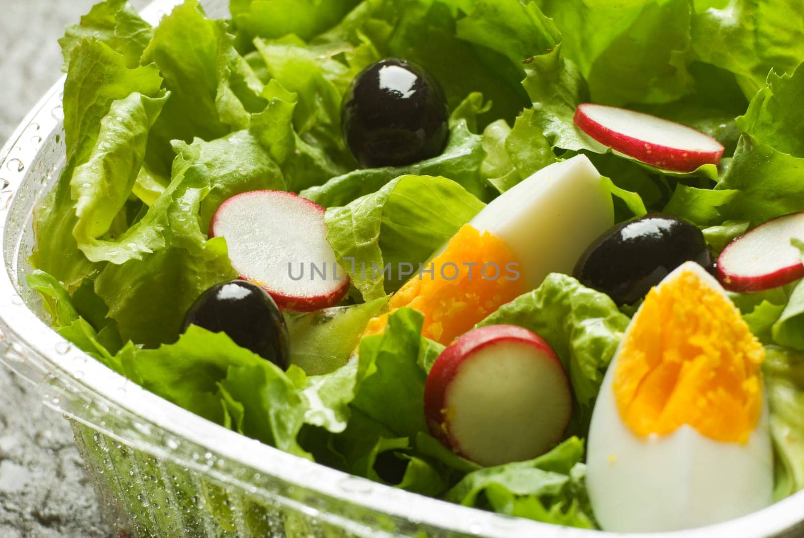 fresh green salad with black olive, egg and radish close up