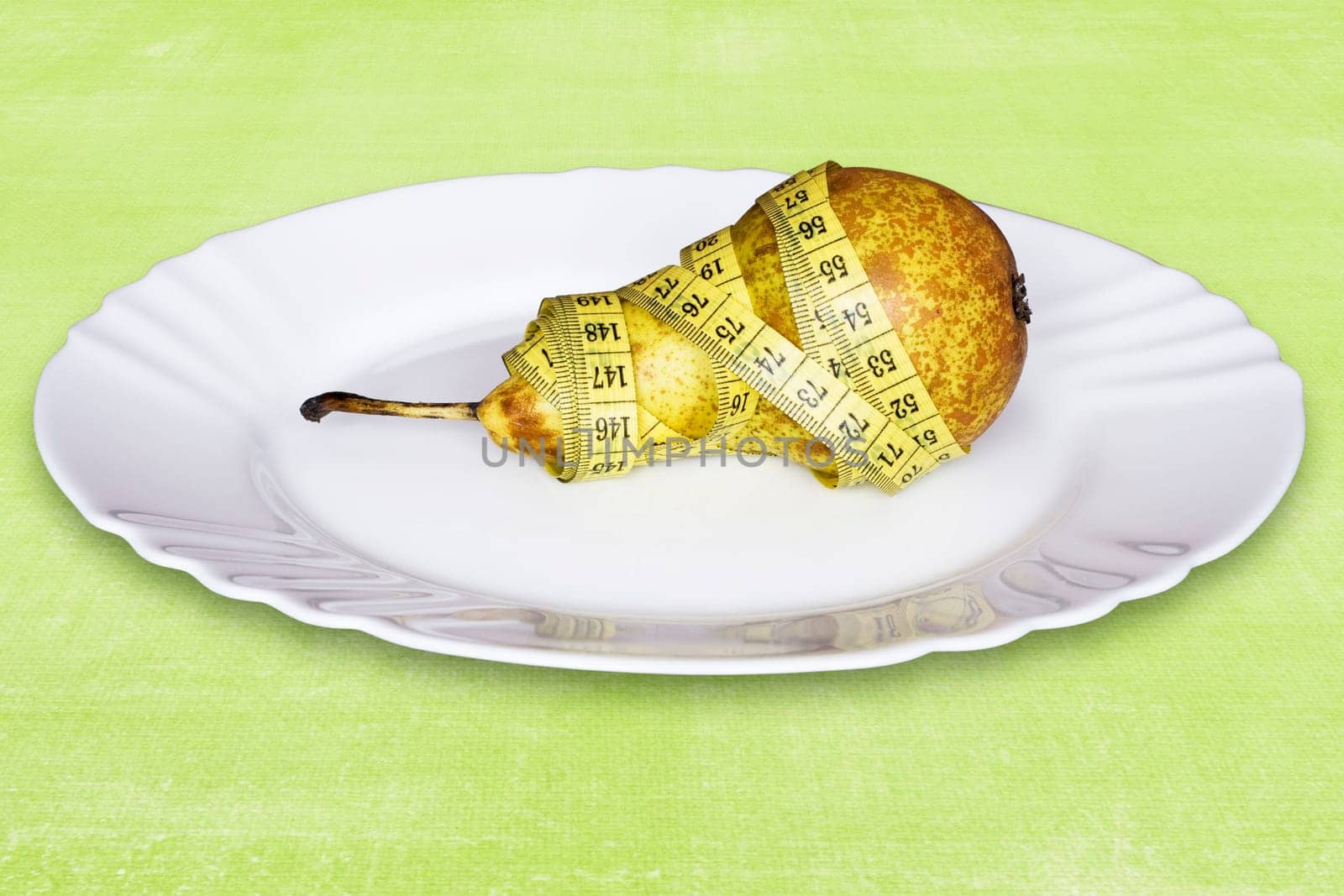 healthy pear with measure tape,in a plate