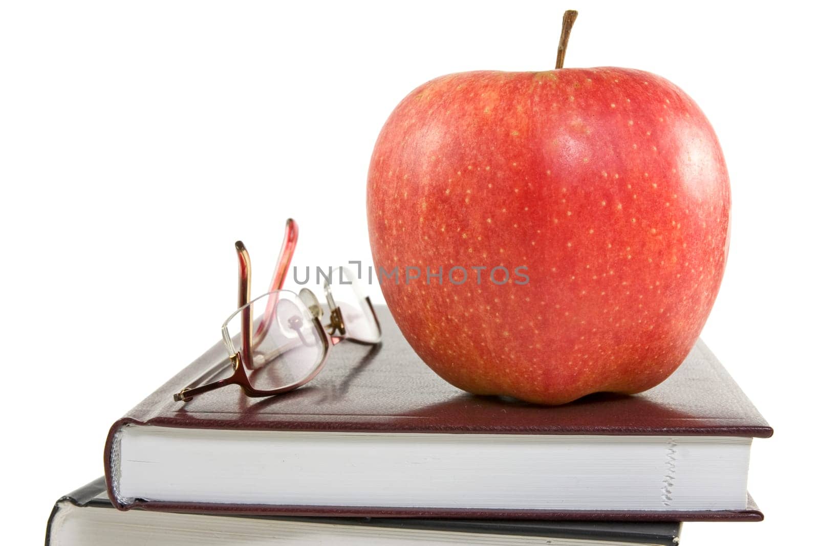 red apple and glasses on the books. isolated on white background