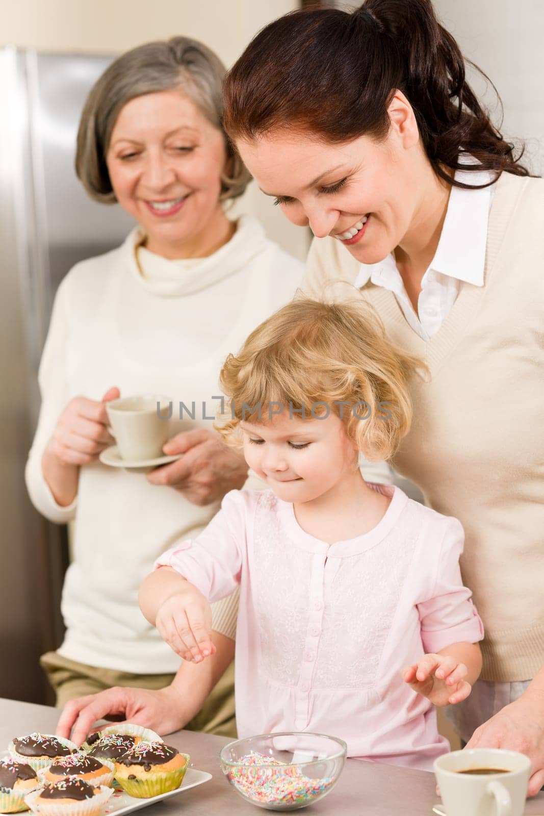 Mother and daughter decorating cupcakes sprinkles happy together at home