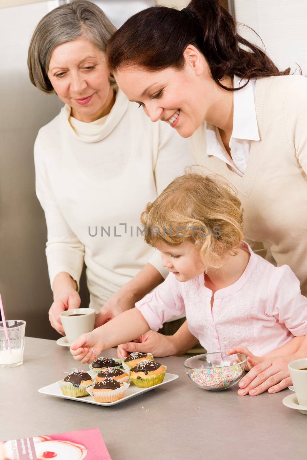 Mother and daughter decorating cupcakes sprinkles happy together at home