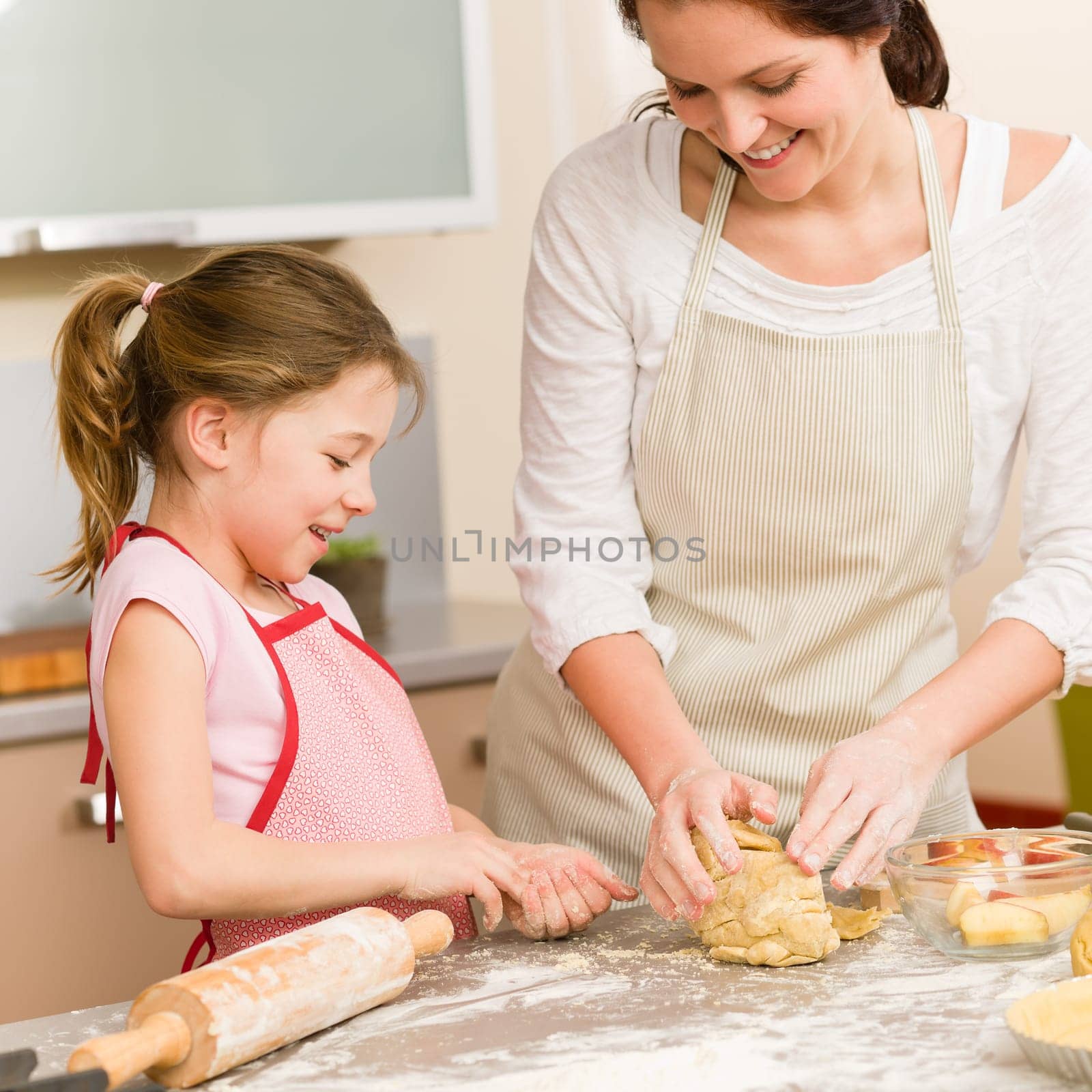 Mother and daughter prepare dough baking apple cake happy together