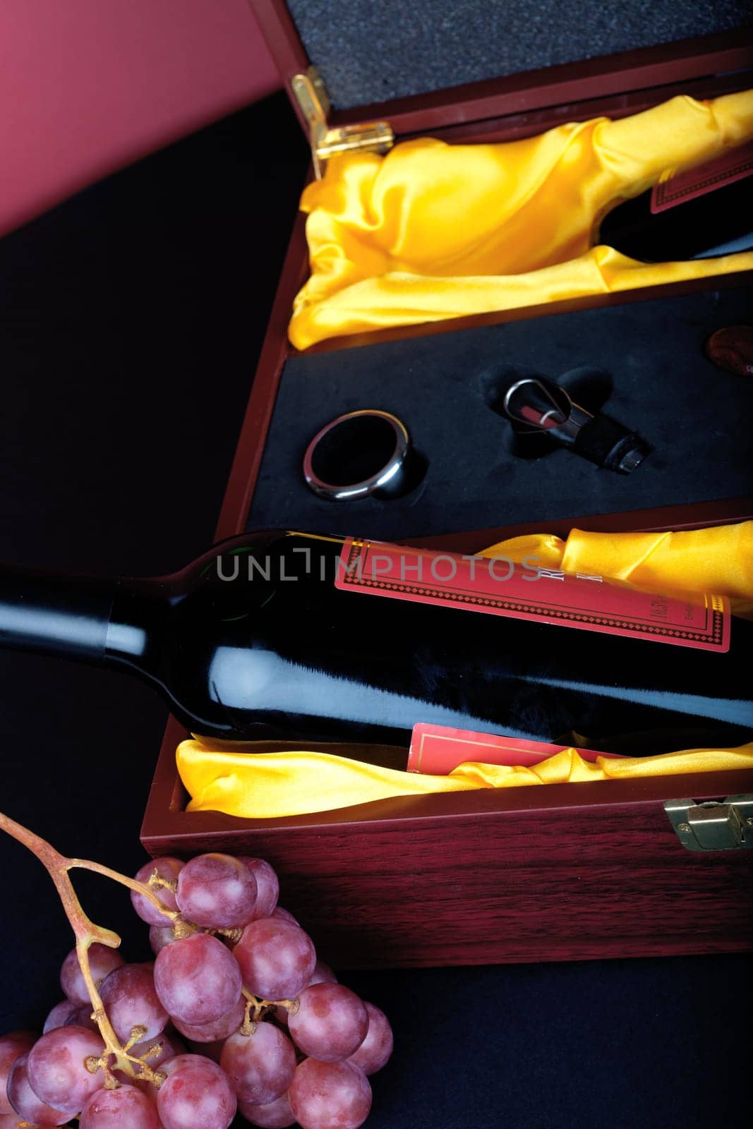 Wine bottle in decorative gift box decorated with grapes